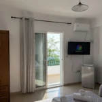 Triple room with a sea view balcony, double bed, and modern amenities at Kolagji Rooms in Lukovë.