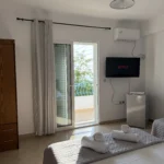 Comfortable sea view triple room featuring a flat-screen TV, mini-fridge, and AC on the Albanian Riviera.