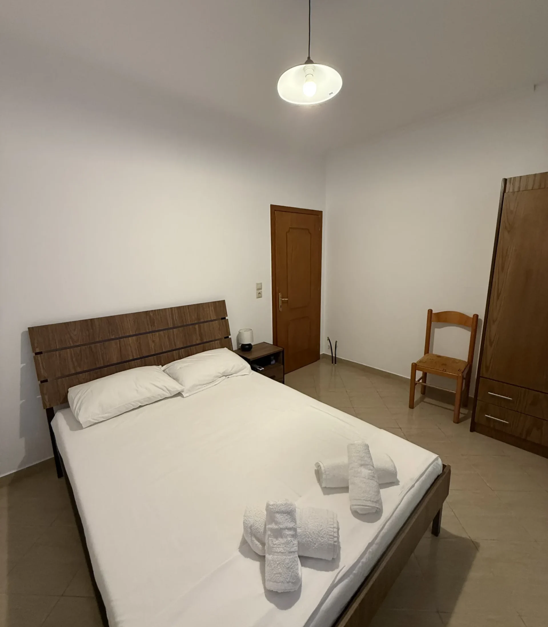 Comfortable double bed and wooden wardrobe in the Budget Double Room at Kolagji Rooms in Lukovë.