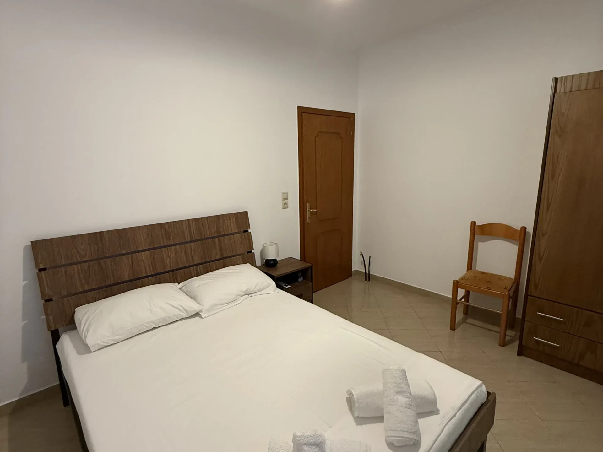 Comfortable double bed and wooden wardrobe in the Budget Double Room at Kolagji Rooms in Lukovë.
