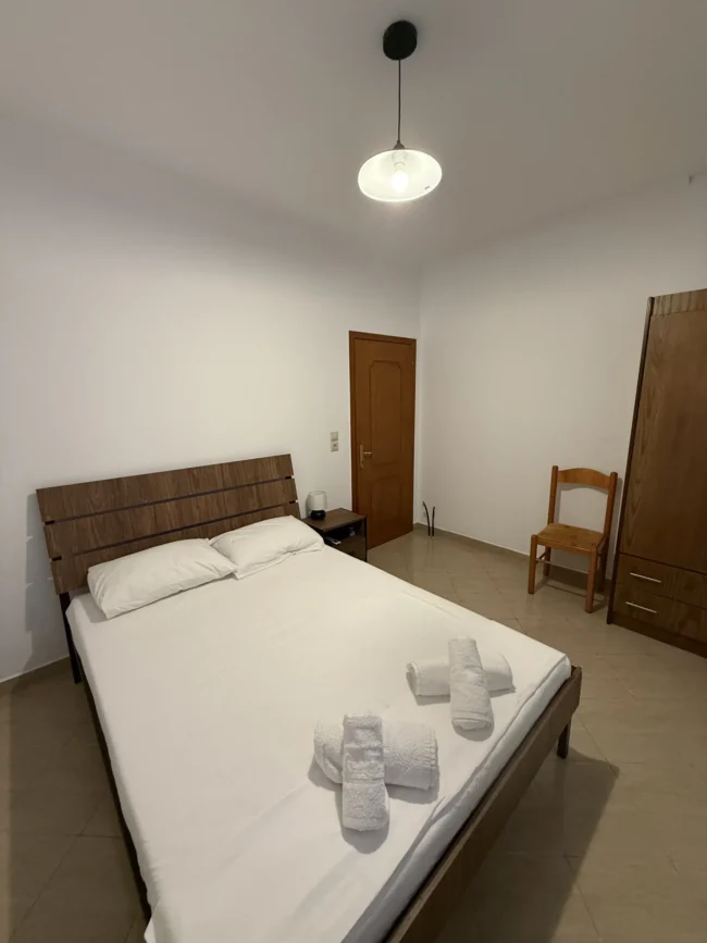 Comfortable double bed and wooden wardrobe in the Budget Double Room at Kolagji Rooms in Lukovë.