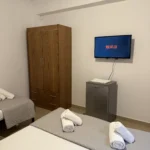 Air conditioning, flat-screen TV, and room amenities inside the Lukovë budget triple accommodation.