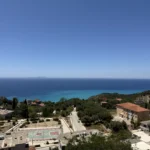 Wide panoramic daytime view of Lukovë village, coastal mountains, and the expansive Ionian Sea from our rooms.