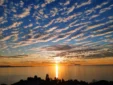 Golden evening sun reflecting on the calm ocean waters beneath a stunning cloud-filled sky in Lukovë, Albania.