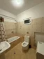 Clean shared bathroom with a bathtub, shower, and modern amenities for budget rooms in Lukovë.