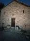 Front facade and wooden door of the historic stone church of Shën e Premte in Lukovë at dusk.
