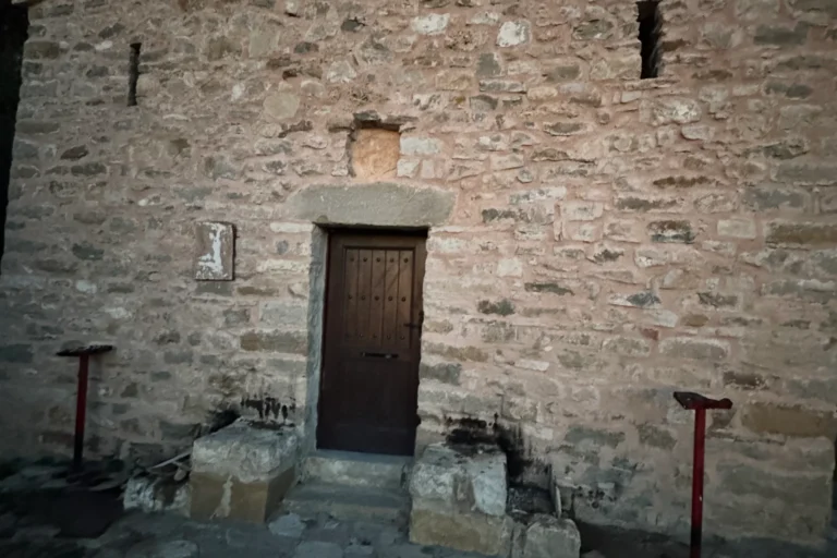 Front facade and wooden door of the historic stone church of Shën e Premte in Lukovë at dusk.