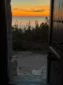 View looking out the open wooden door of Shën e Premte church towards a beautiful coastal sunset in Lukovë.