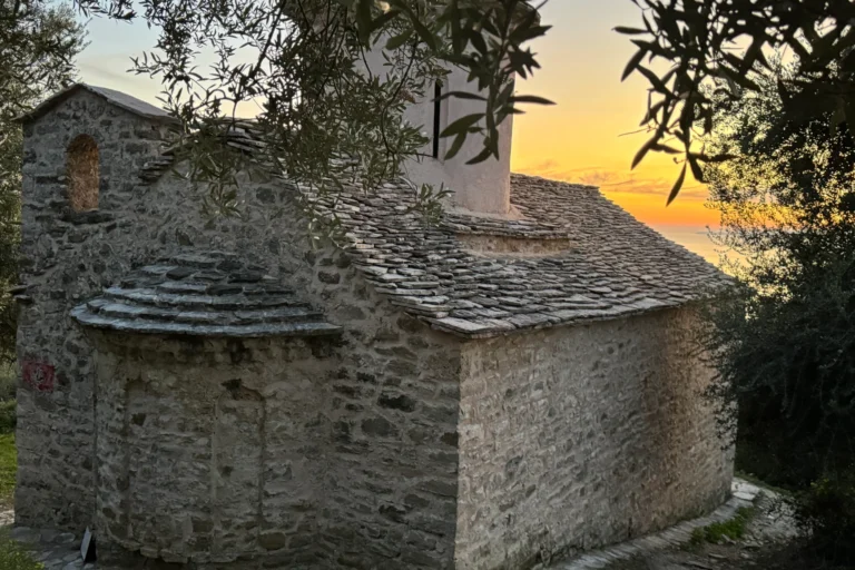 Traditional stone architecture and slate roof of the Shën e Premte church during a beautiful Lukovë sunset.