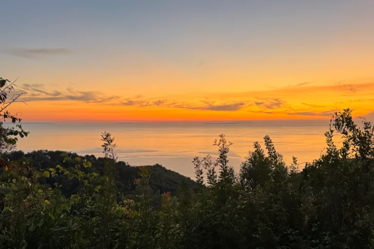 Vibrant orange and yellow sunset over the ocean horizon viewed from the hills of Lukovë, Albania.
