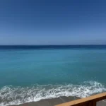Turquoise waters of the Ionian Sea seen from a wooden viewing deck at Shpella Beach in Lukovë.