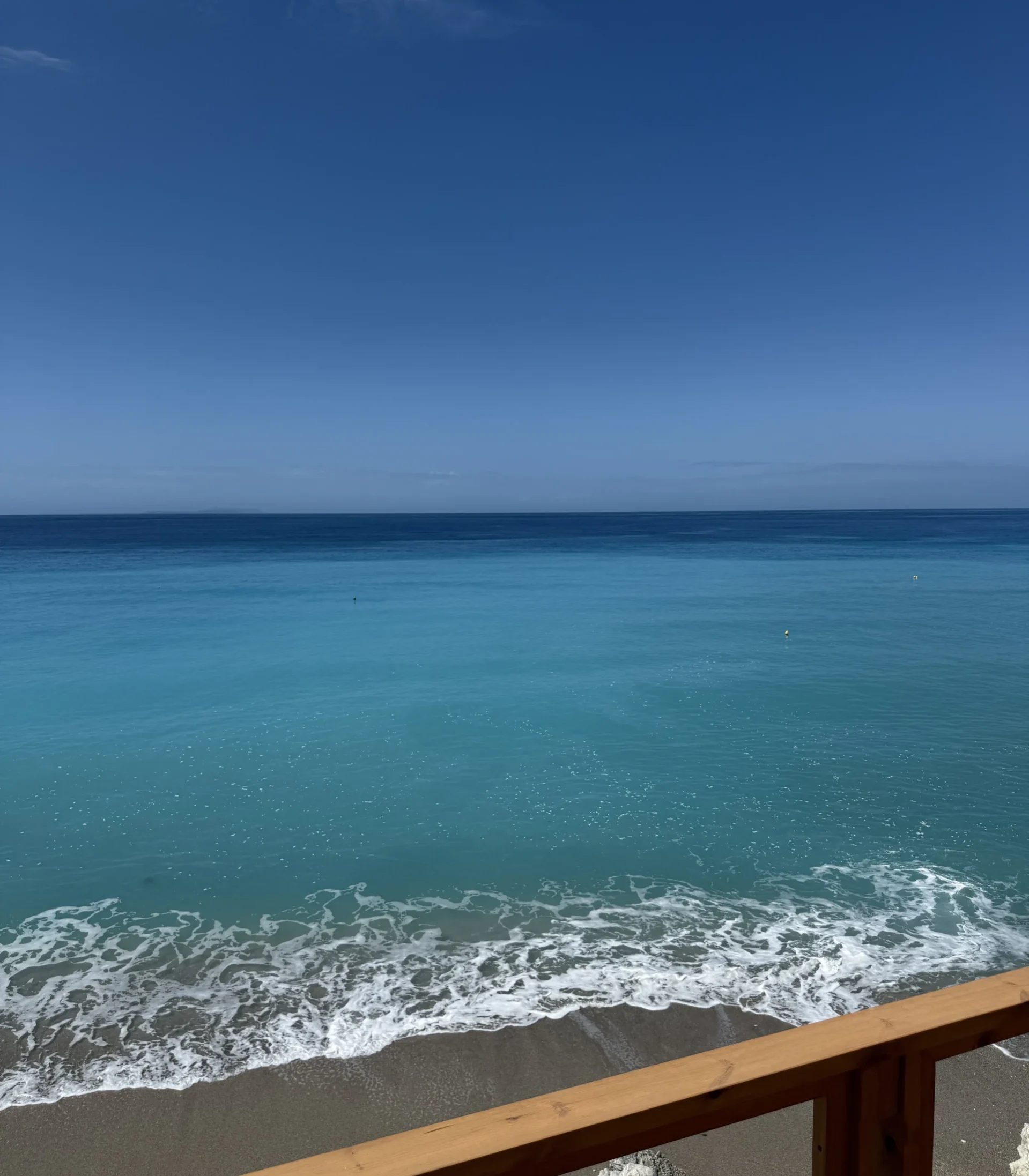Turquoise waters of the Ionian Sea seen from a wooden viewing deck at Shpella Beach in Lukovë.