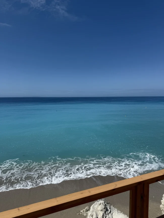 Turquoise waters of the Ionian Sea seen from a wooden viewing deck at Shpella Beach in Lukovë.