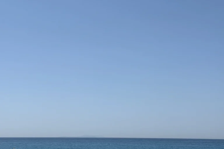 Traditional straw beach umbrellas providing shade at the stunning Shpella Beach in Albania.