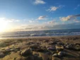 Low angle view of beach pebbles and sand during a beautiful coastal sunset at Shpella Beach.