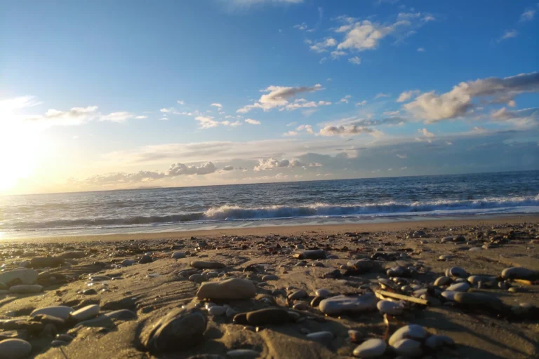 Low angle view of beach pebbles and sand during a beautiful coastal sunset at Shpella Beach.
