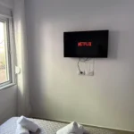Wall-mounted TV with Netflix above the bed in the Triple Room with Outdoor View at Kolagji Rooms.