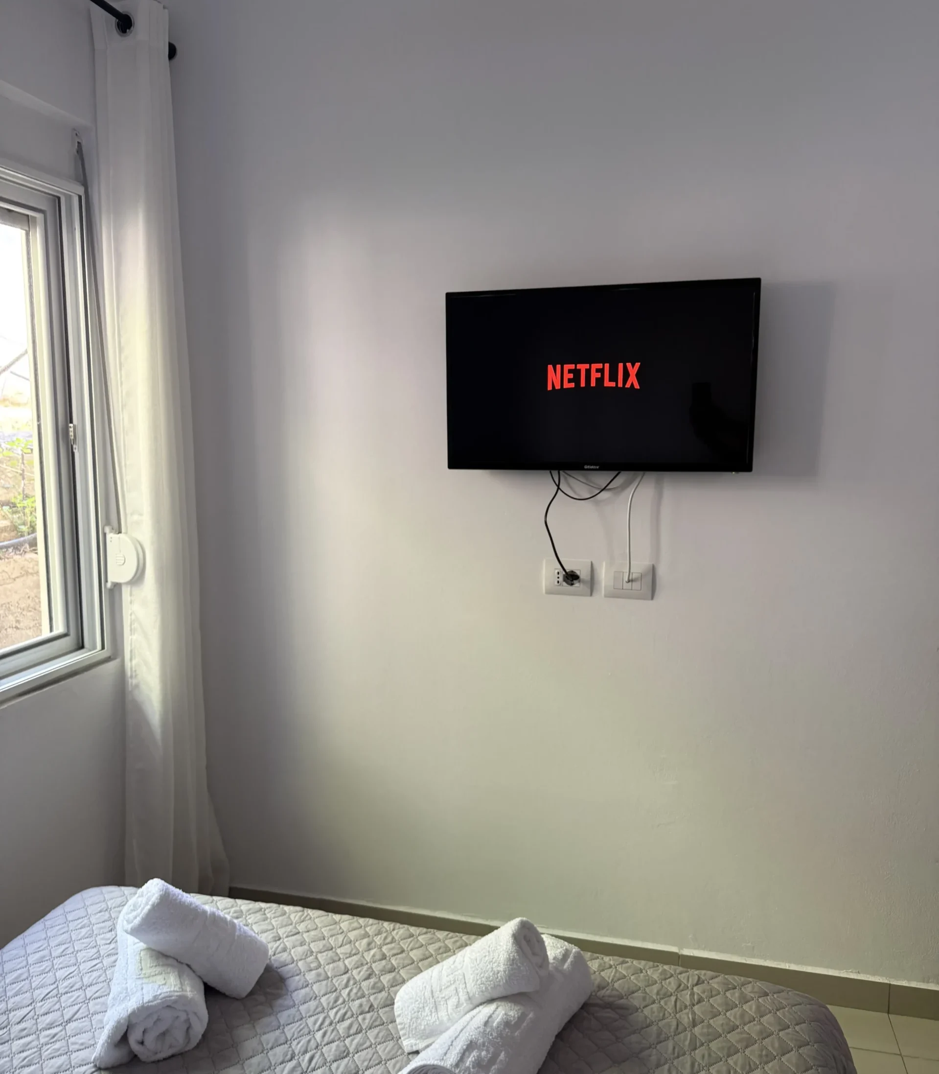 Wall-mounted TV with Netflix above the bed in the Triple Room with Outdoor View at Kolagji Rooms.