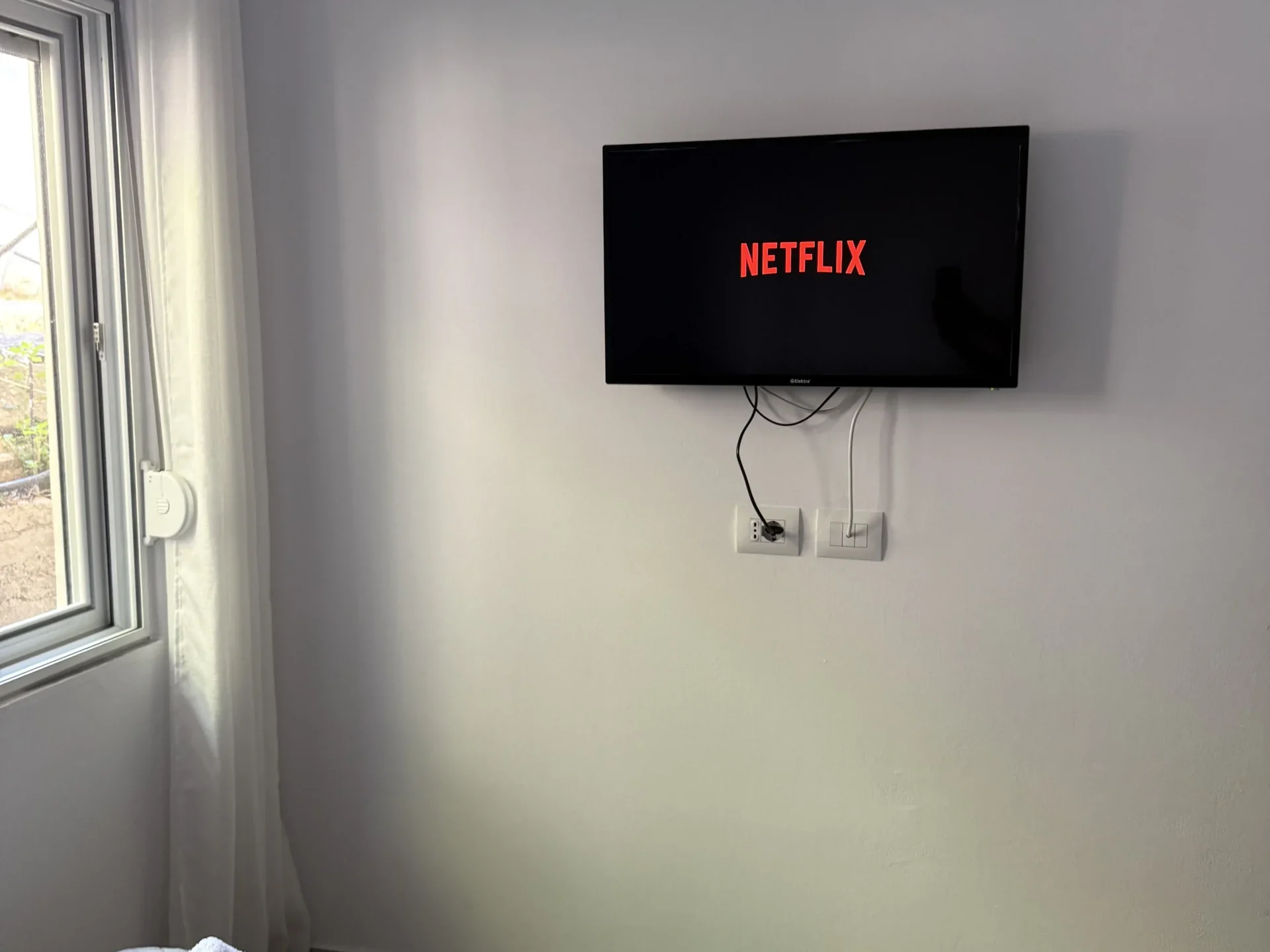 Wall-mounted TV with Netflix above the bed in the Triple Room with Outdoor View at Kolagji Rooms.