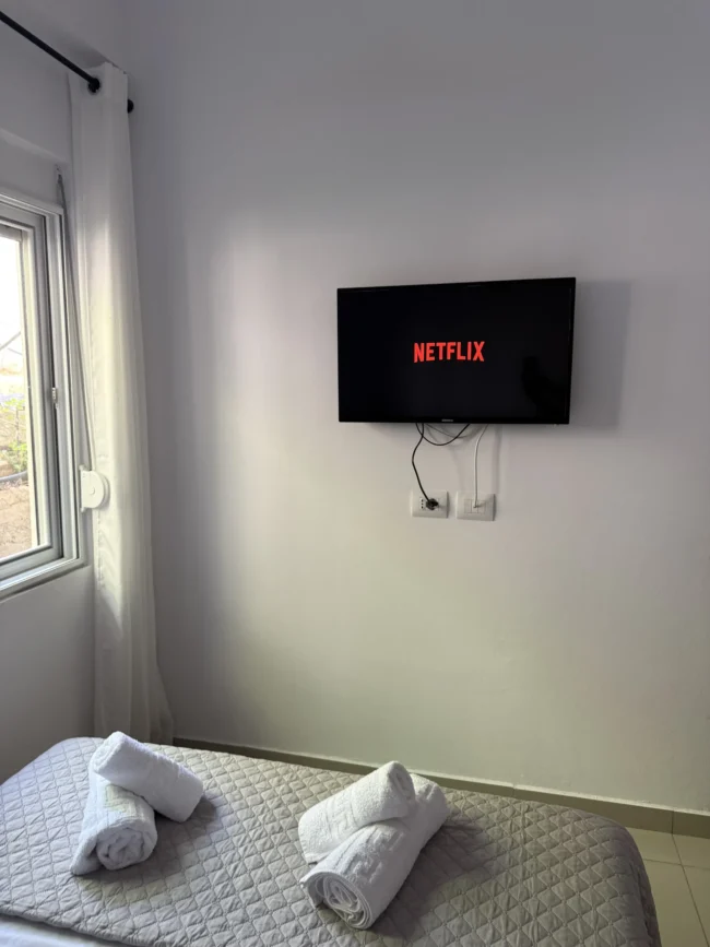 Wall-mounted TV with Netflix above the bed in the Triple Room with Outdoor View at Kolagji Rooms.