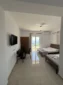 Flat-screen TV and dining area in the affordable Lukovë triple room, with doors opening to the Ionian Sea.
