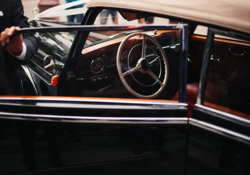 Chauffeur opening the door of a classic car for the convenient airport drop-off service at Kolagji Rooms.