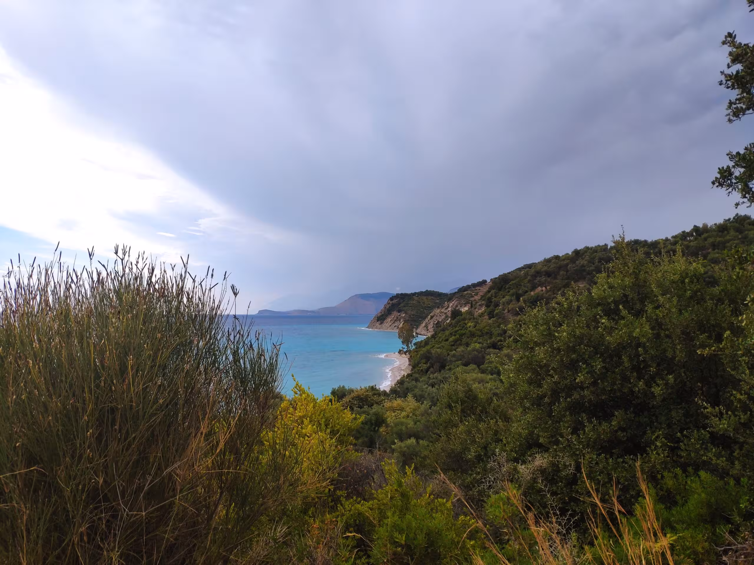 Elevated view of the coastline and turquoise water at Lumra Beach surrounded by lush green foliage.